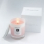 Milos Whispers of Love Artisan Scented Candle by elenianna elenianna Milos Whispers of Love luxury Greek candle, shown lit in its glass vessel next to its white luxury gift box.