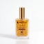 Shimmering Golden Elixir by Mastic Spa, hydrated and glow, 100ml bottle with gold cap on a reflective surface against a dark background.